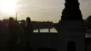 Wanita mendentingkan kaca mata saat mereka menikmati matahari terbenam di jembatan di atas sungai Seine dengan latar belakang Menara Eiffel, di Paris (29/3/2021). (AP Photo/Thibault Camus)