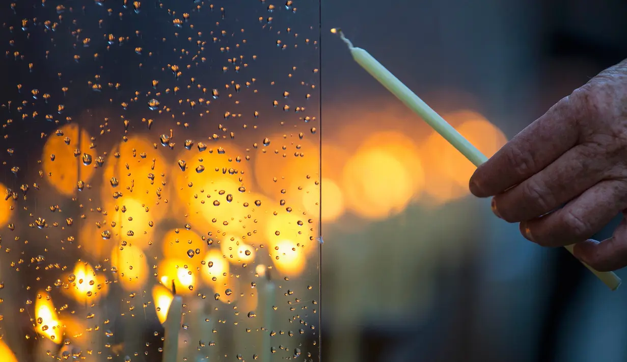 Seorang warga menyalakan lilin saat memperingati 26 tahun runtuhnya Tembok Berlin di sepanjang jalan Bernauer Strasse, Jerman, Senin (9/11). (REUTERS/Hannibal Hanschke)