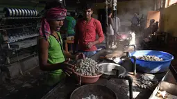 Pekerja pabrik merebus kepompong murbei di pabrik sutra tertua di Srinagar, Kashmir, India, Senin (30/7). (Tauseef MUSTAFA/AFP)