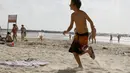 Seorang bocah Israel berusaha berlari menyelamatkan diri dari pantai yang diduga akan menjadi sasaran roket Hamas, Israel, Senin (14/07/2014) (AFP PHOTO/GALI TIBBON)
