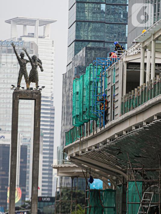 Pekerja menyelesaikan proyek revitalisasi Halte TransJakarta Bundaran HI, Jakarta, Senin (3/10/2022). Gubernur DKI Jakarta Anies Baswedan memastikan revitalisasi halte Transjakarta Tosari di kawasan Bundaran HI terus berlanjut. Proyek revitalisasi itu terus berlanjut meskipun sempat diprotes sejarawan JJ Rizal karena dianggap menutupi Patung Selamat Datang di Bundaran HI. (Liputan6.com/Faizal Fanani)