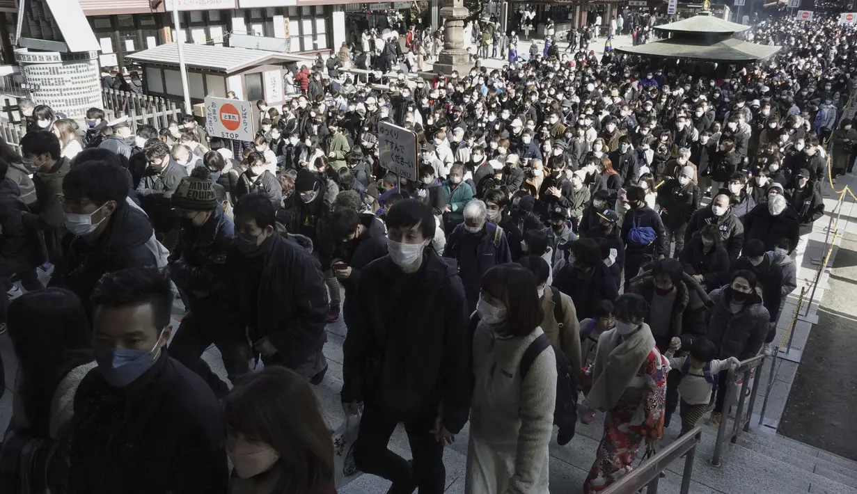 Pengunjung berjalan untuk berdoa memohon keberuntungan selama "hatsumode", atau kunjungan pertama mereka tahun ini ke kuil atau kuil, di kuil Kawasaki Daishi di Kawasaki, dekat Tokyo, Senin (3/1/2022). (AP Photo/Eugene Hoshiko)