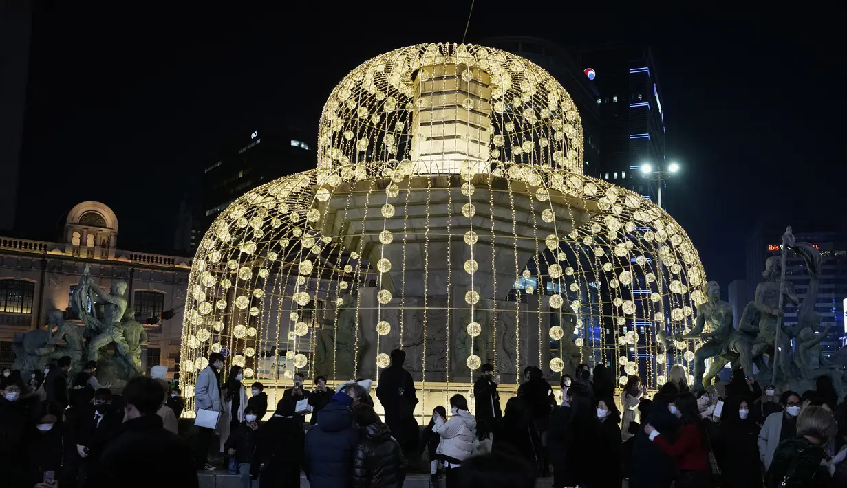 Orang-orang berkumpul di sekitar dekorasi Natal yang diterangi lampu pada Malam Natal di Seoul, Korea Selatan, Jumat (24/12/2021). (AP Photo/Ahn Young-joon)
