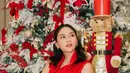 Berpose di depan pohon Natal, Jessica Mila kenakan pleated dress merah yang anggun effortless. Rambutnya ditata half updo yang pancarkan aura cantik natural [@jscmila]