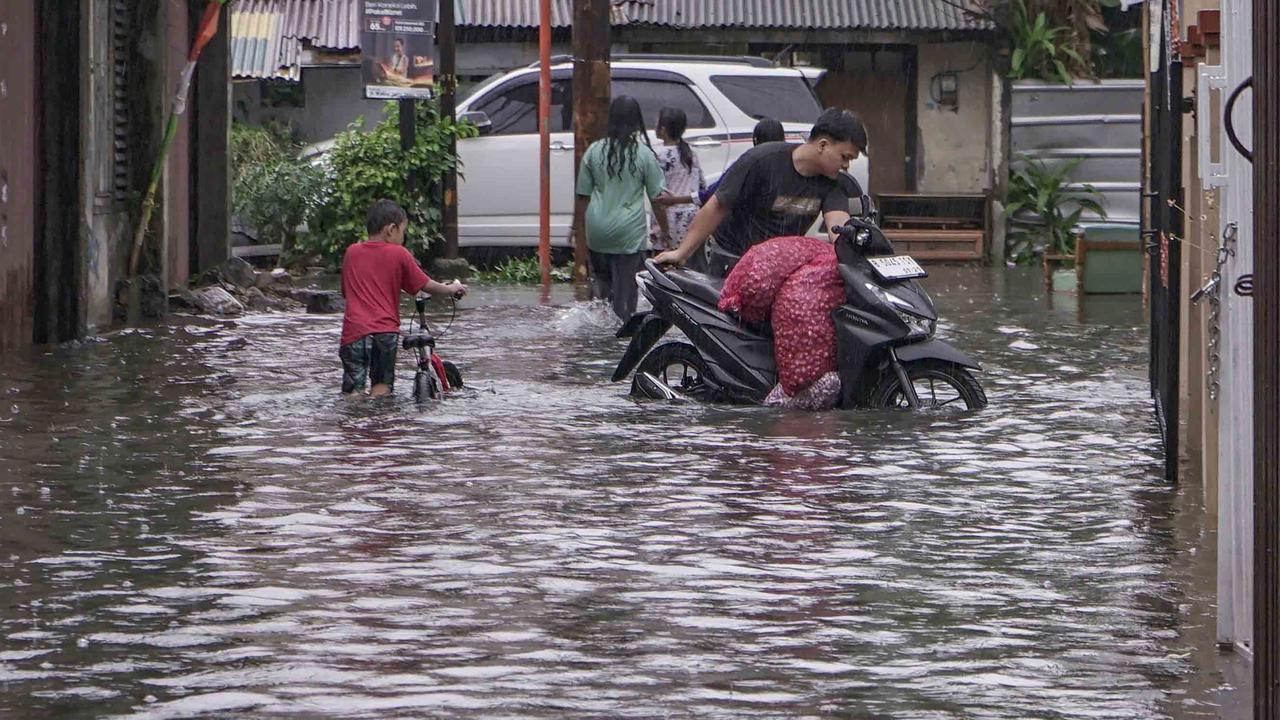 FOTO: Drainase Meluap, Warga Pasar Rebo Terobos Genangan