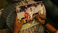 Fan asal Singapura meminta tanda tangan pada foto lawas asisten pelatih Timnas Indonesia, Kurniawan Dwi Yulianto. (Bola.com/Muhammad Iqbal Ichsan)
