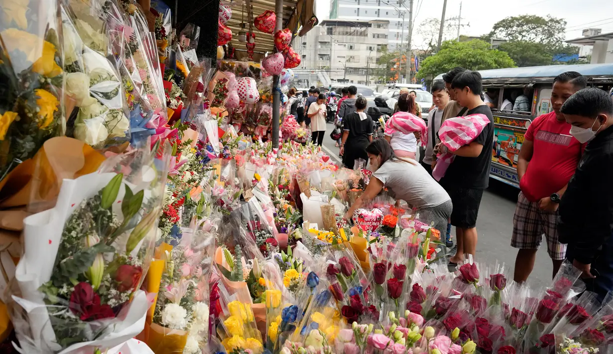 Orang-orang berbelanja di pasar bunga sepanjang jalan ramai di Manila, Filipina, Senin (13/2/2023). Harga bunga naik karena tingginya permintaan sehari sebelum Hari Valentine. (AP Photo/Aaron Favila)