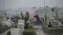 Seorang warga berdoa di tengah hujan deras di makam keluarganya di lahan khusus korban Covid-19 di TPU Keputih, Surabaya, Jawa Timur, Kamis (7/1/2020). Total sembuh 17.006 dan 1.256 meninggal dunia. (AFP/Juni Kriswanto)