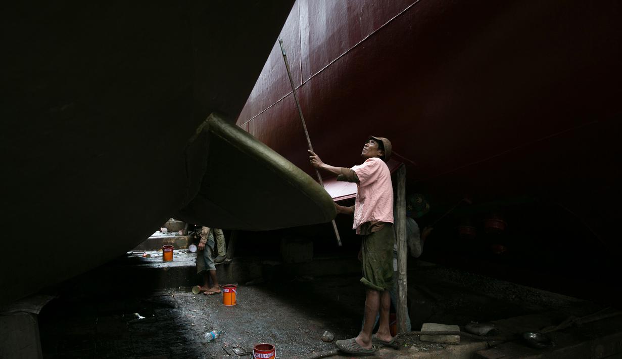Seorang pekerja saat mengecat sebuah kapal di galangan kapal di tepi Sungai Yangon, yang terletak di pinggiran Yangon, Myanmar (30/7/2019). (AFP Phot/Sai Aung Main)