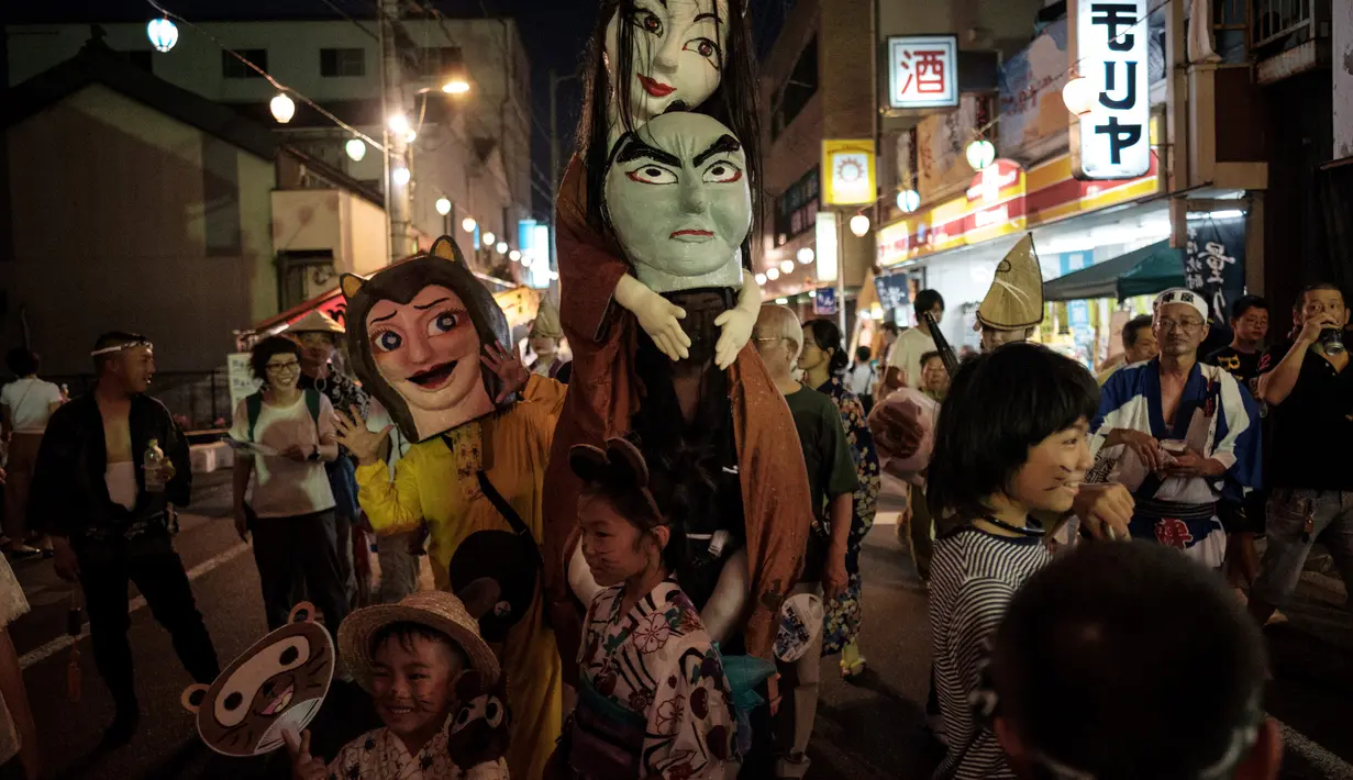 Peserta mengenakan kostum hantu saat festival Awa Odori di Kota Miyoshi, Jepang (16/8). Acara ini biasanya dimulai pada siang hari, namun pertunjukan utamanya baru dimulai pada petang hingga malam hari. (AFP Photo/Yasuyoshi Chiba)
