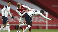 Martin Odegaard dari Arsenal, tengah, dan Tanguy Ndombele dari Tottenham berebut bola selama pertandingan sepak bola Liga Inggris di Stadion Emirates di London, Inggris, Minggu, 14 Maret 2021. (Nick Potts / Pool via AP)