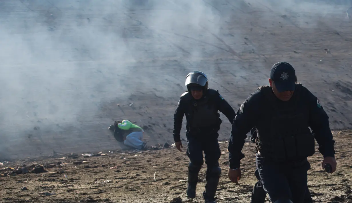 Seorang migran Honduras tergeletak di tepi sungai ketika polisi Meksiko menjauh dari gas air mata yang ditembakkan oleh agen AS di perbatasan antara Meksiko dan AS di Tijuana, Meksiko (25/11). (AP Photo/Ramon Espinosa)