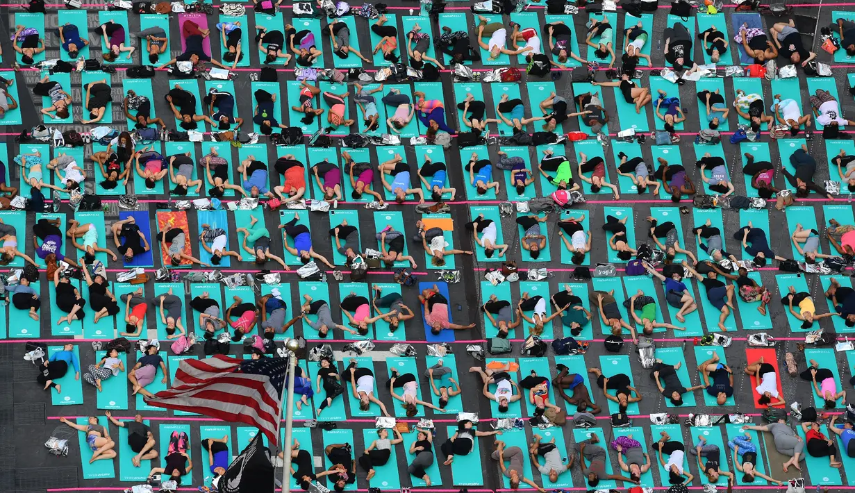 Warga berlatih yoga di tengah jalan Times Square, New York pada 'Summer Solstice' atau hari dengan siang terpanjang di musim panas, Rabu (21/6). Acara tersebut menandai Hari Yoga Internasional yang jatuh pada 21 Juni. (TIMOTHY A. CLARY/AFP)