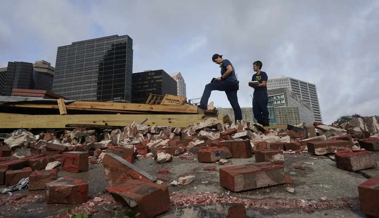 Petugas pemadam kebakaran menaksir kerusakan saat mereka melihat melalui puing-puing setelah sebuah bangunan runtuh akibat dampak Badai Ida di New Orleans, Louisiana, Senin (30/8/2021). Badai Ida ini sebagai salah satu badai paling kuat yang pernah melanda Amerika Serikat.  (AP Photo/Eric Gay)