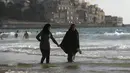 Dua warga Palestina berjalan di pinggir 7/2015). Selama Idul Fitri, pemerintah Israel mengizinkan warga Palestina untuk berwisata di sepanjang garis pantai Mediterania. (REUTERS/Baz Ratner)