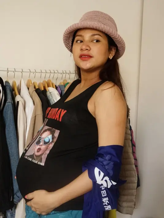 Seperti gaya grunge gemas dengan tank top nuansa hitam dengan graphic rock and roll. Yang dipasangkan dengan celana denim dan topi bernuansa girly warna pink. (Foto: Instagram @indahpermatas)