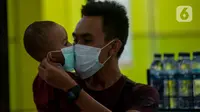 Calon penumpang kereta api mengenakan masker saat berada di Stasiun Gambir, Jakarta Pusat, Jumat (31/01). Dalam rangka pencegahan Virus Corona, PT Kereta Api Indonesia (persero) melakukan sosialisasi kepada penumpang dengan membagi-bagikan masker di stasiun Gambir. (merdeka.com/Imam Buhori)