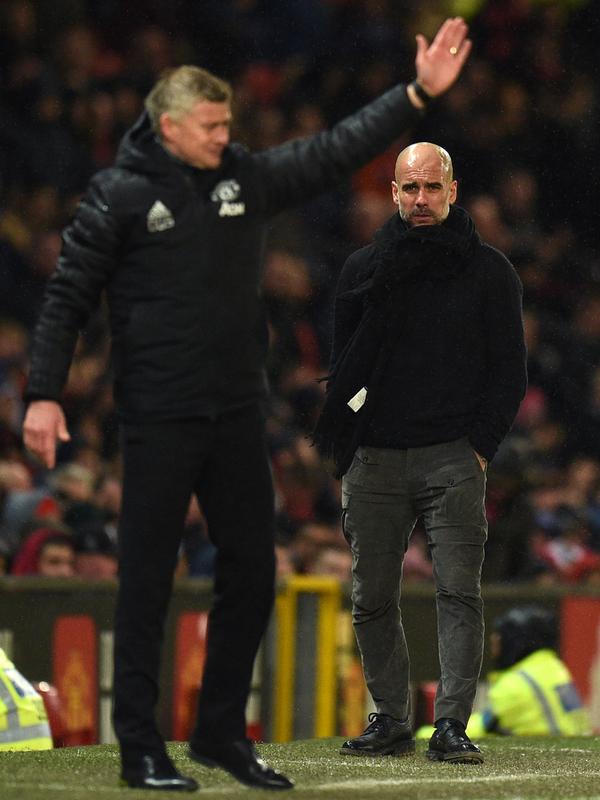 Pelatih Manchester City Pep Guardiola (kanan) dan manajer Manchester United Ole Gunnar Solskjaer saat menyaksikan para pemain mereka bertanding pada laga Liga Inggris di Old Trafford, Manchester, Inggris, Minggu (8/3/2020). Manchester United menang 2-0. (Oli SCARFF/AFP)