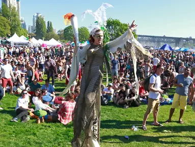 Seorang wanita berjalan membawa ganja besar saat merayakan acara legalisasi ganja 4/20 di Sunset Beach, Vancouver, Kanada (20/4). Legalisasi ini telah menjadi janji kampanye utama perdana menteri yang baru terpilih, Justin Trudeau. (AFP/Jeff Vinnick)