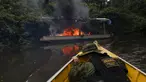 Petugas lingkungan Brasil saat berlindung dari kapal yang dibakar selama operasi terhadap penambangan emas ilegal di perairan hutan hujan Amazon, Roraima, Brasil (16/4). Daerah ini merupakan tempat dimana suku Yanomami tinggal. (REUTERS / Bruno Kelly)