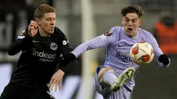 Gelandang Barcelona Gavi berebut bola dengan gelandang Eintracht Frankfurt Kristijan Jakic pada laga leg pertama perempat final Liga Europa 2021/22 di Deutsche Bank Park, Jumat dini hari WIB (8/4/2022). Frankfurt dan Barcelona berbagi skor 1-1 . (AP Photo/Michael Probst)