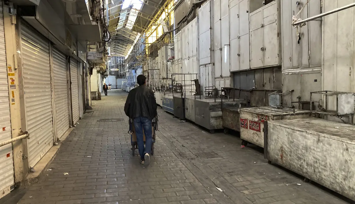 Seorang pria mendorong gerobaknya melewati toko-toko yang tutup di Grand Bazaar Teheran, Iran, Selasa (15/11/2022). Aksi mogok dapat semakin memberikan tekanan pada pemerintah Iran, yang sejauh ini menolak tuntutan para demonstran. (AP Photo/Vahid Salemi)