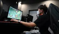 Seorang pria bermain game komputer di sebuah kafe internet di Beijing, China, Jumat (10/9/2021). Pejabat China memanggil perusahaan game, termasuk dua yang terbesar yaitu Tencent dan NetEase, untuk membahas pembatasan lebih lanjut pada industri game online. (GREG BAKER/AFP)