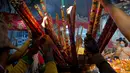 Umat mempersembahkan dupa di sebuah kuil untuk menandai dimulainya Tahun Baru Imlek di Ta Khmao, provinsi Kandal, Kamboja, Jumat (12/2/2021). Meskipun perayaan Imlek biasa dilakukan dengan cara bervariasi di seluruh dunia, maka tahun ini sangat berbeda karena pandemi COVID-19. (TANG CHHIN Sothy/AFP)
