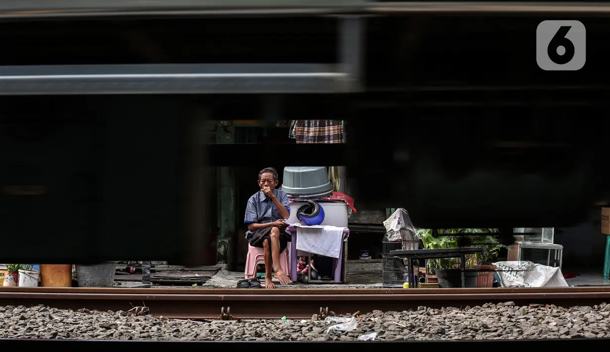Seorang warga duduk saat kereta melintas di bantaran rel kawasan pemukiman padat Pejompongan di tengah pandemi COVID-19, Jakarta, Kamis (28/1/2020). Dibandingkan  dengan  hasil  sensus  sebelumnya,  jumlah  penduduk  DKI  Jakarta terus  meningkat. (Liputan6.com/Johan Tallo)