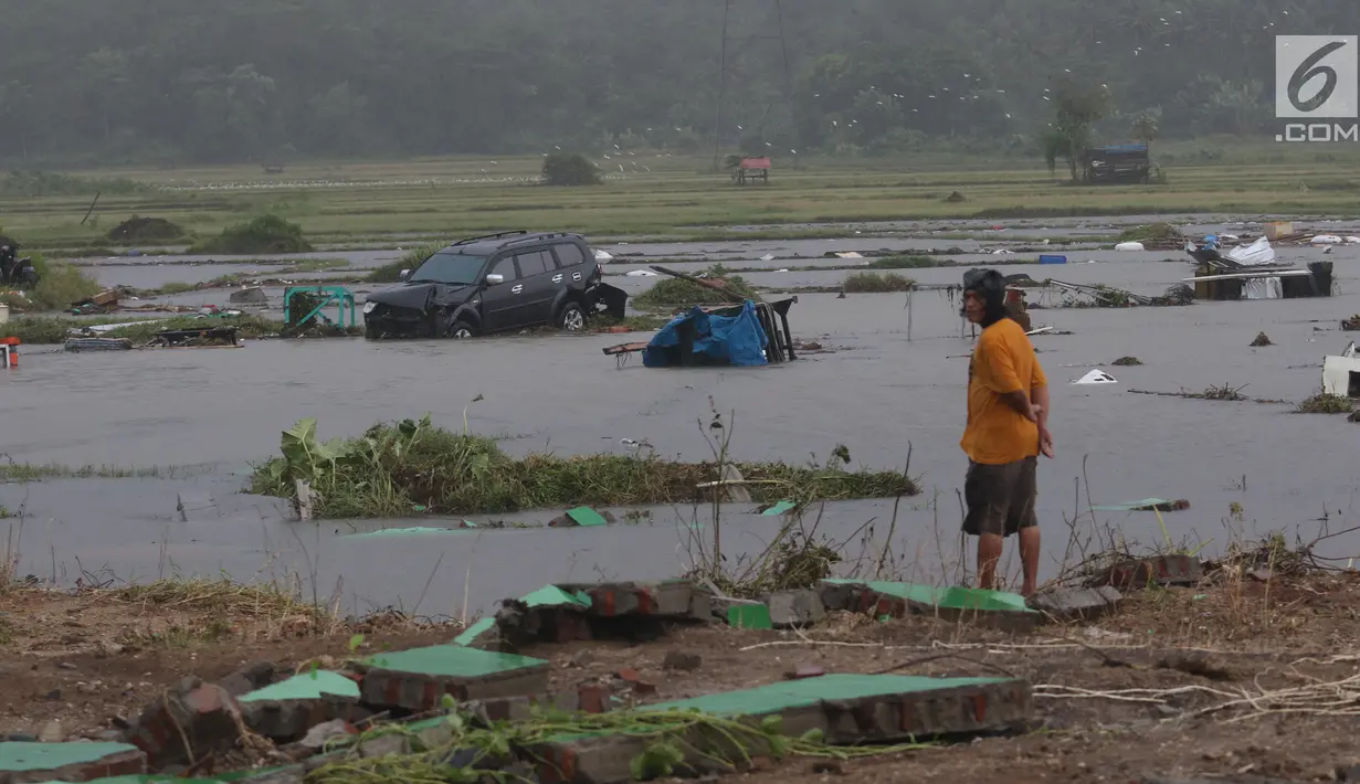 Seorang warga melihat mobil yang terbawa ke tengah sawah setelah tsunami melanda kawasan Anyer, Banten, Minggu (23/12). Tsunami menerjang pantai di Selat Sunda, khususnya di daerah Pandenglang, Lampung Selatan, dan Serang. (Liputan6.com/Angga Yuniar)