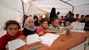 Anak-anak Suriah membuka bukunya saat mengikuti kegiatan belajar di dalam tenda yang diubah menjadi ruang kelas di kamp pengungsi di kota Maarrat Misrin di Provinsi Idlib, Suriah (6/10/2020). (AFP/Omar Haj Kadour)