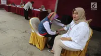 Petugas medis Puskesmas memeriksa tekanan darah petugas Kelompok Penyelenggara Pemungutan Suara (KPPS) yang bertugas saat pemungutan suara ulang di TPS 49 Rengas, Ciputat Timur, Tangsel, Rabu (24/4). Pemeriksaan untuk antisipasi menurunnya kesehatan fisik akibat kelelahan. (merdeka.com/Arie Basuki)