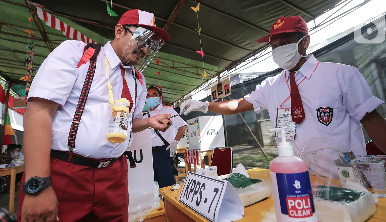 Petugas KPPS berseragam sekolah diteteskan tinta di kelingking pada Pilkada Tangerang Selatan di TPS 49 Cendana Residence, Pamulang, Rabu (9/12/2020). TPS yang mengusung Rindu Sekolah Lagi (Kisah-Kasih di Sekolah) terapkan protokol kesehatan pada Pilkada Serentak 2020. (Liputan6.com/Fery Pradolo)