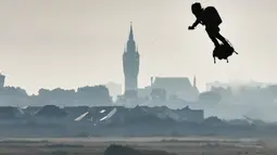 Penemu Prancis, Franky Zapata terbang menggunakan hoverboard bertenaga jet melewati menara di balai kota Calais dari Sangatte menuju Teluk St. Margaret di Dover pada Minggu (4/8/2019). Zapata berhasil menyeberangi Selat Inggris dalam waktu 20 menit dengan papan terbang ciptaannya (Denis Charlet/AFP)