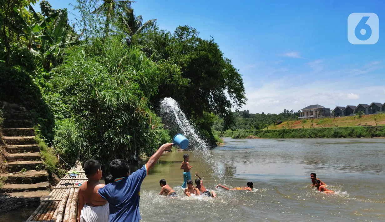 Anak-anak bermain pada aliran Sungai Cisadane di kawasan Keranggan, Setu, Tangerang Selatan, Banten, Minggu (20/3/2022). Cuaca panas terik dimanfaatkan mereka untuk berendam sambil bermain. (merdeka.com/Arie Basuki)