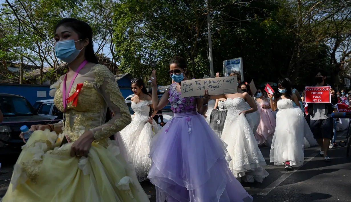 Sejumlah wanita Myanmar memakai gaun pengantin memegang plakat selama demonstrasi menentang kudeta militer 1 Februari di Yangon (10/2/2021). Aksi unjuk rasa terus digelar para demonstran yang mengabaikan larangan demonstrasi oleh militer. (AFP/ Ye Aung Thu)