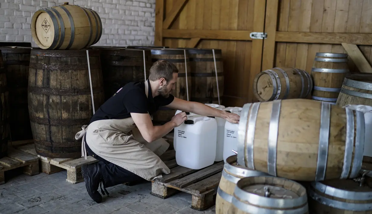 Manajer Waterloo Microdistillery, Edward Martin membawa jerigen alkohol di Mont-Saint-Jean Farm, Waterloo, Belgia, Selasa (7/4/2020). Di tengah pandemi virus corona COVID-19, pabrik sopi dan wiski Mont-Saint-Jean Farm beralih memproduksi alkohol medis. (Kenzo TRIBOUILLARD/AFP)