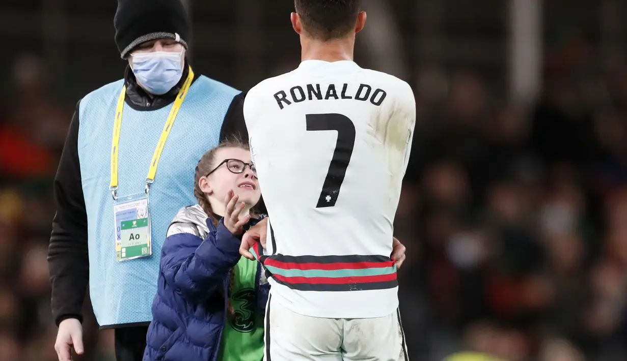 Tak lama, Ronaldo melepas jersey-nya untuk diberikan kepada fans cilik perempuan yang nekat itu. (AP/Peter Morrison)
