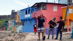 Wisatawan berswafoto saat mengunjungi lokasi syuting video klip Despacito di La Perla, San Juan, Puerto Rico, 22 Juli 2017. Lokasi syuting dalam video Despacito yang eksotis membuat orang penasaran untuk berkunjung ke sana. (Ricardo ARDUENGO/AFP)