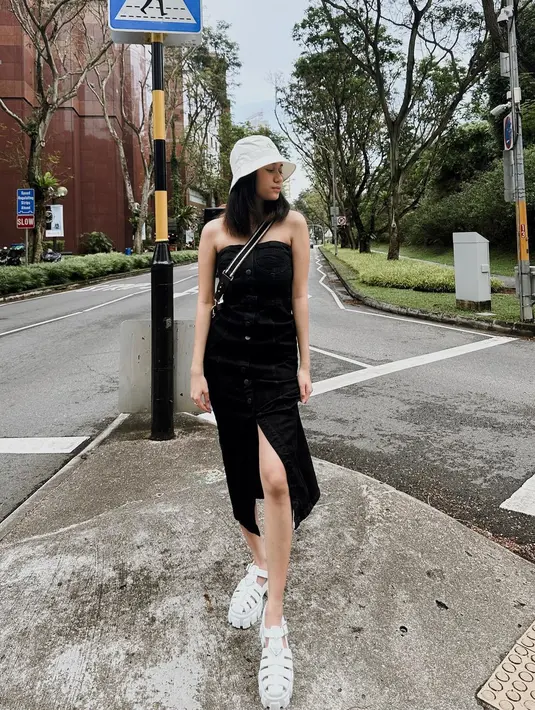 Tube dress jeans hitam makin kece dengan aksesori bucket hat dan sepatu sandal warna putih. [Instagram/azizahsalsha_]