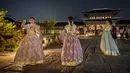 Pengunjung mengenakan gaun tradisional Korea, hanbok sambil berpose saat kunjungan malam ke Istana Gyeongbokgung di Seoul, 4 Oktober 2019. Kunjungan malam tersedia pada minggu ketiga dan keempat setiap bulan mulai dari 26 April sampai 31 Oktober, kecuali pada bulan Agustus. (Photo by Ed JONES / AFP)