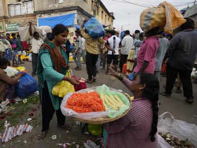 Seorang wanita menawar dengan penjual bunga di pasar grosir di Bengaluru, India, Rabu (13/4/2022). Orang-orang telah kembali beraktivitas normal setelah pihak berwenang mencabut pembatasan COVID-19 termasuk mengenakan masker wajah di tempat-tempat umum. (AP Photo/Aijaz Rahi)