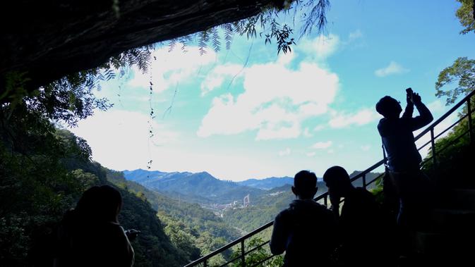 Turis mengambil gambar suasana Kuil Tao  di gua Gunung Yinhe di distrik Xindian, Kota Taipei Baru, Taiwan (29/12/2019). Libur Natal dan Tahun Baru, bagi sebagian warga Taiwan memanfaatkan waktunya untuk berkunjung ke Kuil Tao untuk berwisata maupun memanjatkan doa. (AFP Photo/Sam Yeh)