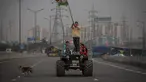 Seorang petani mengibarkan bendera India saat ia berdiri di atas kap kendaraan di jalan bebas hambatan utama di Ghazipur, pinggiran New Delhi, India, Kamis (9/12/2021). Ribuan petani India menghentikan protes mereka selama setahun pada Kamis setelah pemerintah mencabut undang-undang pertanian yang k