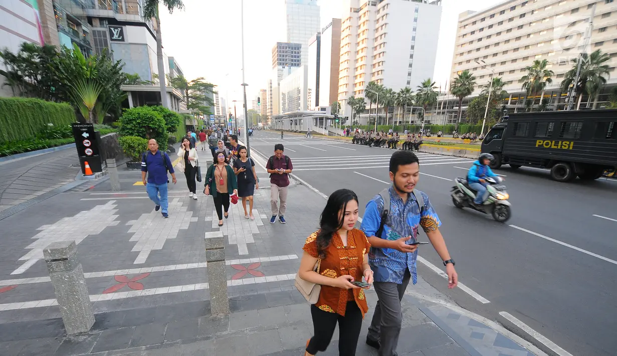 Sejumlah karyawan terpaksa berjalan kaki usai pulang kerja di kawasan Thamrin, Jakarta, Selasa (21/5). Akibat adanya aksi masa tolak hasil pemilu 2019 membuat sejumlah ruas jalan di kawasan tersebut di tutup. (Liputan6.com/Angga Yuniar)
