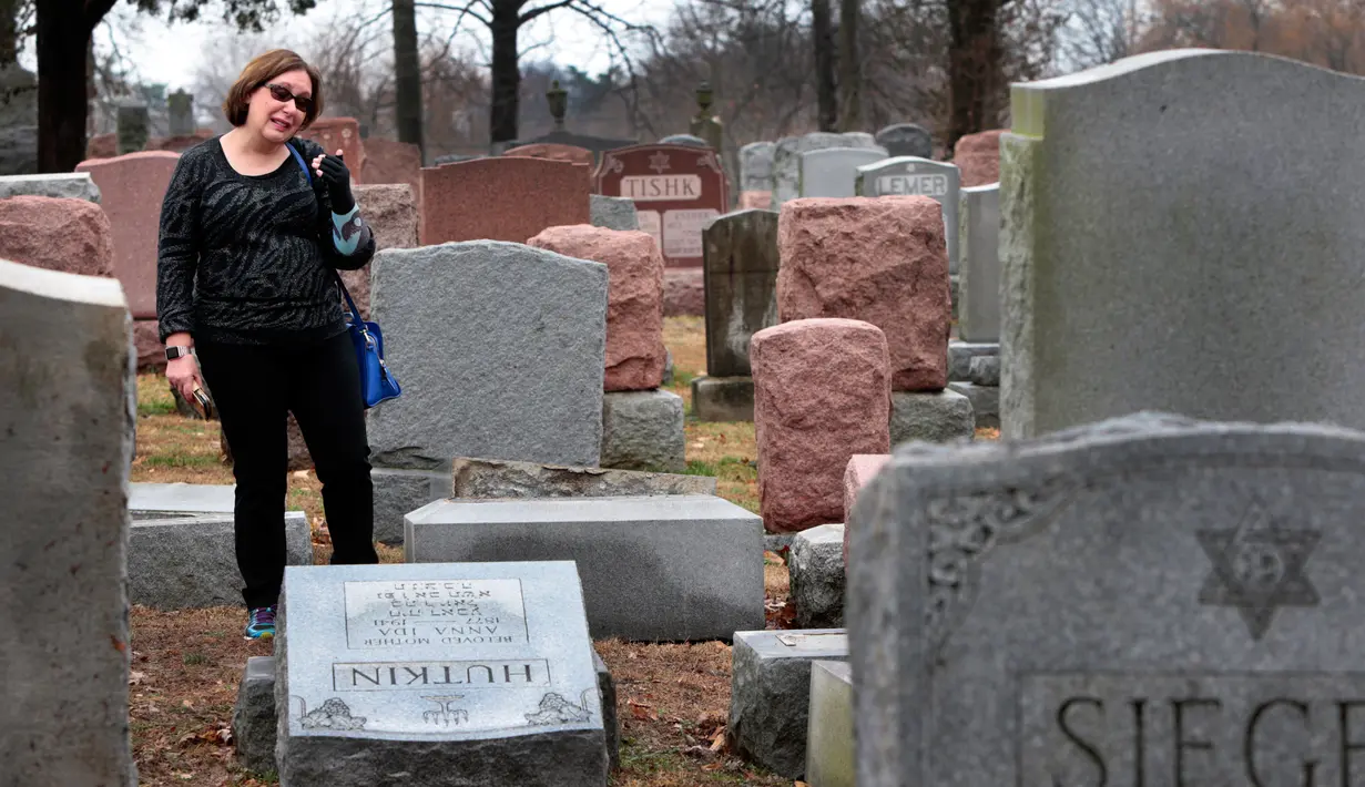 Sally Amon, melihat batu nisan neneknya yang dirusak di Chesed Shel Emeth Cemetery di University City, St Louis, Missouri, (21/2). Setidaknya lebih dari 100 batu nisan rusak di pekuburan itu. (Robert Cohen /St. Louis Post-Dispatch via AP)