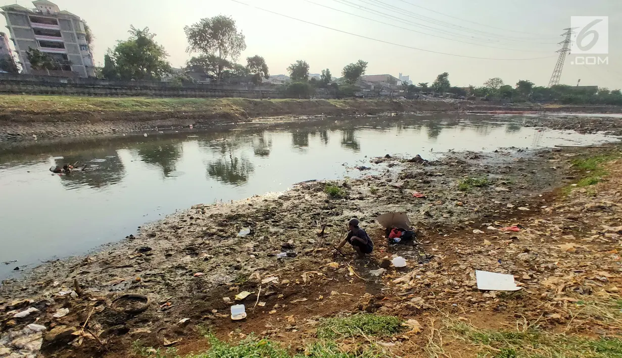 Warga memancing di sekitar Kanal Banjir Barat (KBB) yang mengalami kekeringan di kawasan Tanah Abang, Jakarta, Jumat (12/7/2019). Musim kemarau yang terjadi di Ibu Kota menyebabkan debit air di KBB berkurang sehingga menimbulkan keretakan tanah di sekitarnya. (Liputan6.com/Immanuel Antonius)