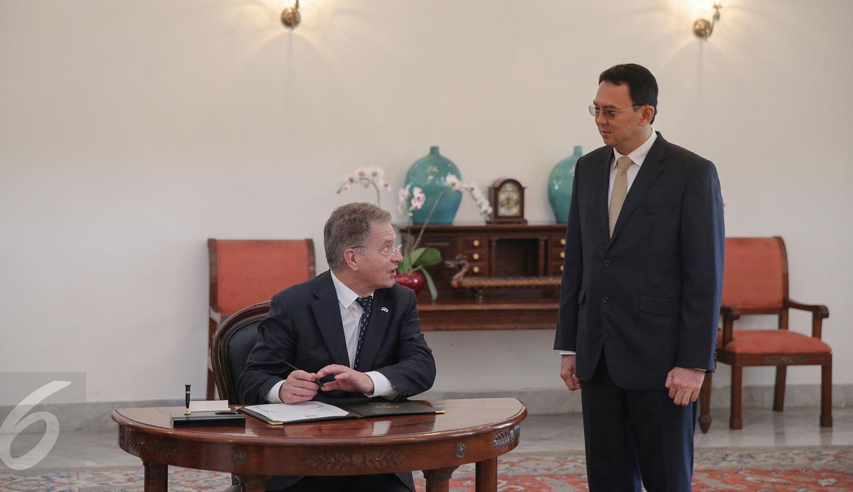 Presiden Finlandia Sauli Vainamo Niinisto (kiri) berbincang dengan Gubernur DKI Basuki Tjahaja Purnama sebelum mengisi buku tamu di Balai Kota DKI Jakarta, Rabu (4/11). Pertemuan keduanya membahas peluang kerjasama. (Liputan6.com/Faizal Fanani)