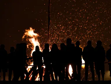 Sejumlah orang mengikuti tradisi malam San Juan's (Saint John) di Gijon, Spanyol, (24/6). Malam San Juan adalah upacara penyucian dimana warga membakar sejumlah benda yang sudah tidak diinginkan. (REUTERS/Eloy Alonso)