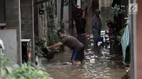 Seorang pria membuang air dengan ember saat banjir merendam kawasan Cipinang Melayu, Jakarta Timur, Senin (5/2). (Liputan6.com/Arya Manggala)